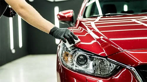 Ceramic coating being applied to a red car